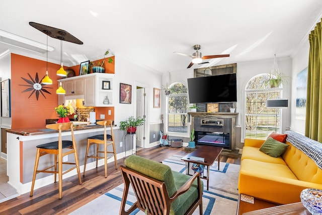 living room with ornamental molding, light hardwood / wood-style flooring, and ceiling fan