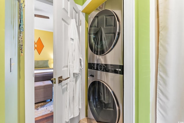 laundry room featuring ornamental molding, hardwood / wood-style floors, and stacked washer and dryer