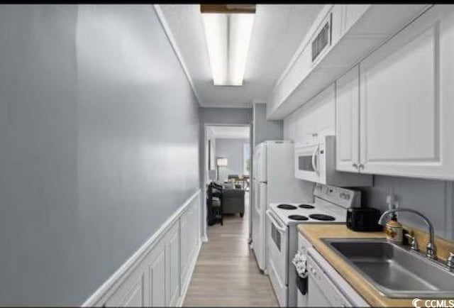 kitchen with white appliances, light hardwood / wood-style floors, sink, and white cabinets