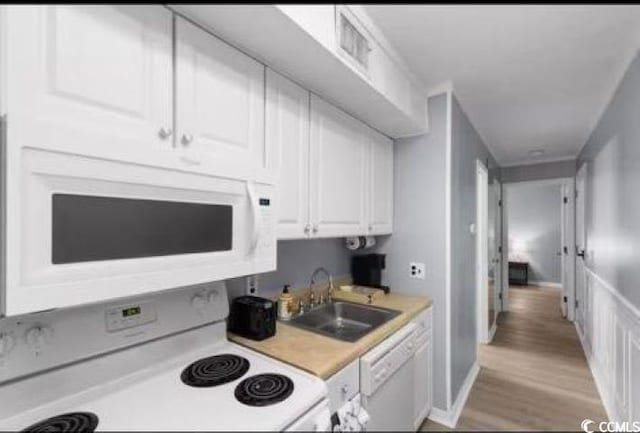 kitchen with white cabinetry, sink, white appliances, and light wood-type flooring