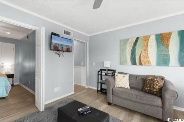 living room with ceiling fan, ornamental molding, and hardwood / wood-style floors