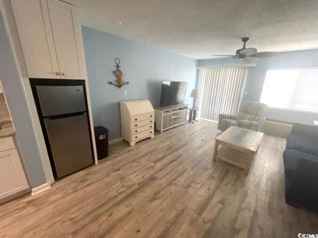 unfurnished living room with ceiling fan, light hardwood / wood-style floors, and a textured ceiling