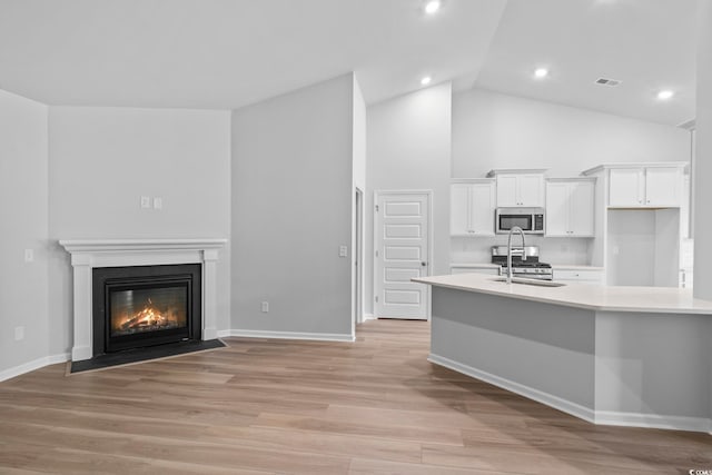 9746 Indigo Creek Blvd, Murrells Inlet, SC 29576 - kitchen featuring stainless steel appliances, light countertops, white cabinetry, light wood finished floors, and high vaulted ceiling