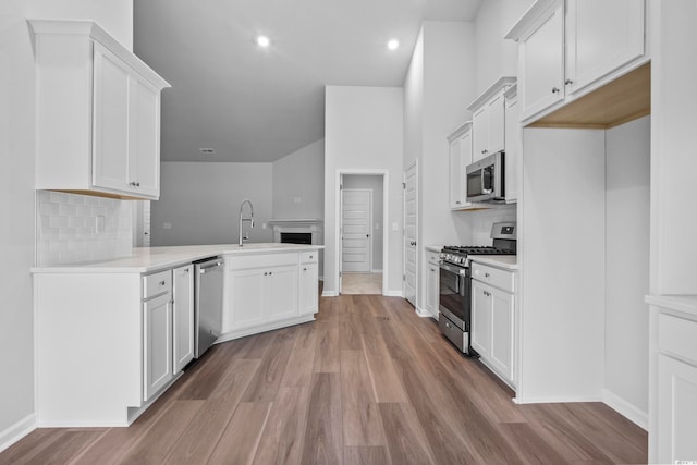 9746 Indigo Creek Blvd, Murrells Inlet, SC 29576 - kitchen featuring appliances with stainless steel finishes, a peninsula, light wood-style flooring, decorative backsplash, and baseboards