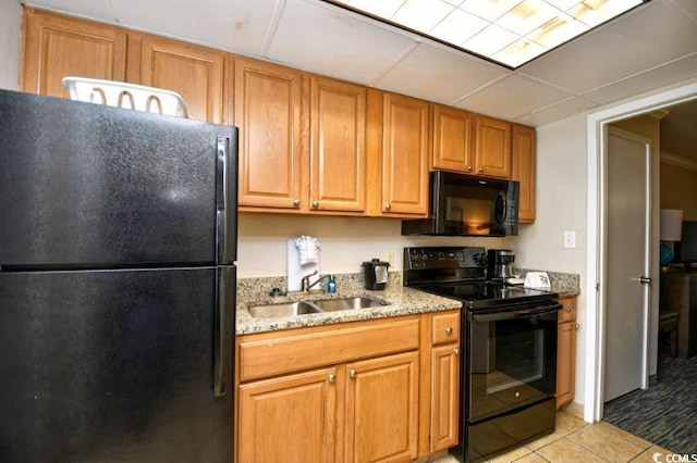 kitchen featuring light stone counters, black appliances, light tile patterned floors, and sink