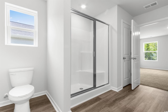 bathroom with hardwood / wood-style floors, toilet, and an enclosed shower