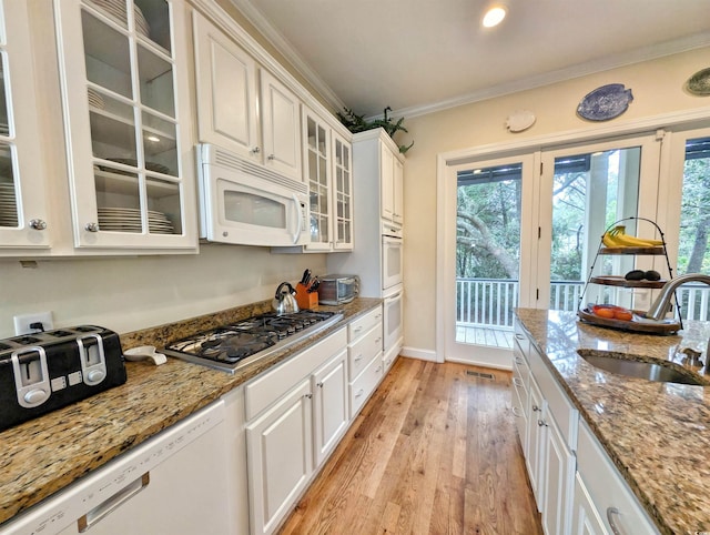 kitchen featuring light stone counters, sink, white cabinets, white appliances, and light hardwood / wood-style flooring