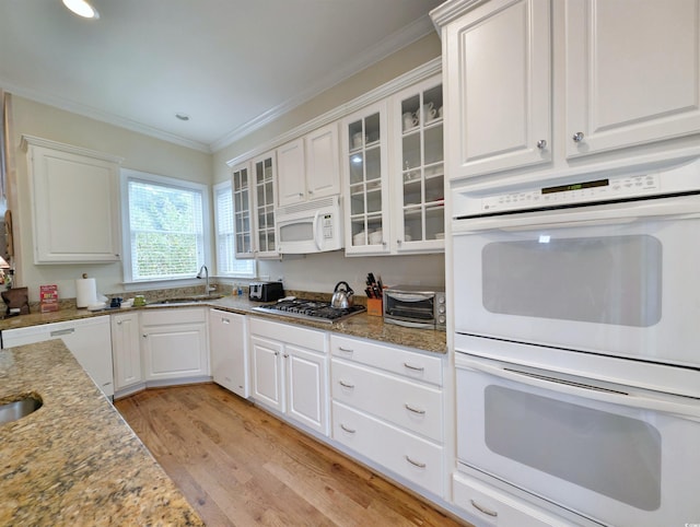 kitchen featuring light stone counters, white cabinets, crown molding, light hardwood / wood-style flooring, and white appliances