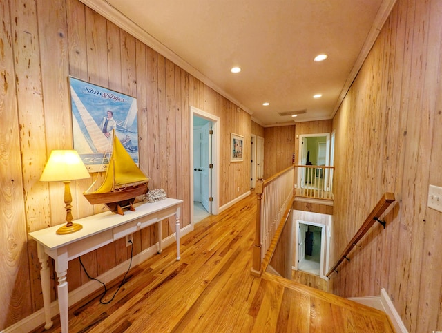 hall featuring wooden walls, light wood-type flooring, and crown molding