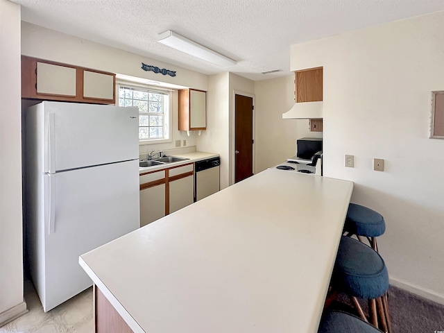 kitchen featuring kitchen peninsula, a kitchen breakfast bar, white appliances, a textured ceiling, and sink