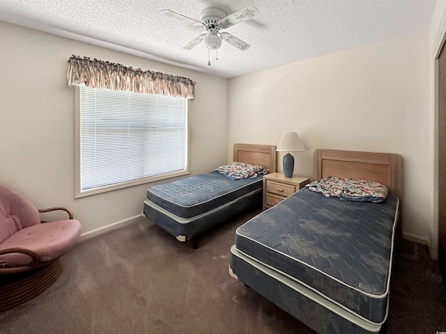 bedroom with ceiling fan, a textured ceiling, and dark colored carpet