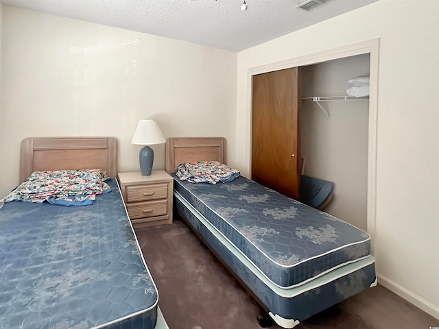 bedroom featuring a closet, dark colored carpet, and a textured ceiling