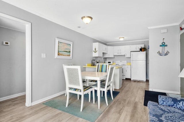 dining space featuring light wood-type flooring and crown molding