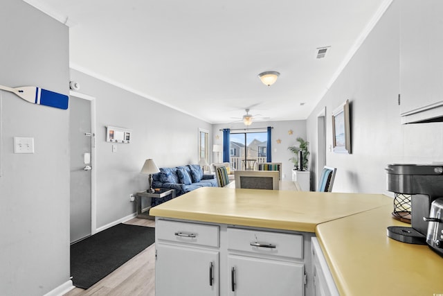 kitchen with white cabinets, light hardwood / wood-style flooring, ceiling fan, and ornamental molding