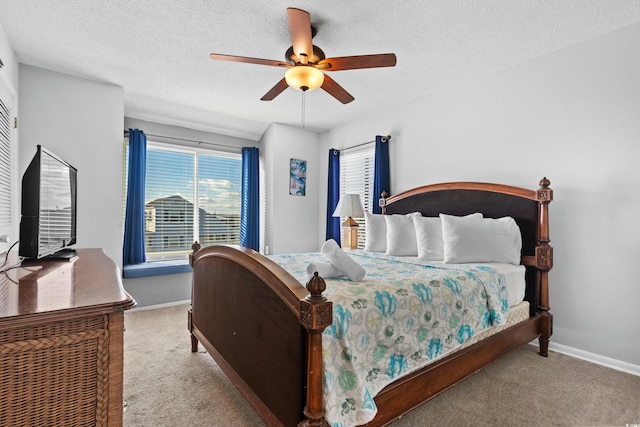 bedroom featuring a textured ceiling, light colored carpet, and ceiling fan