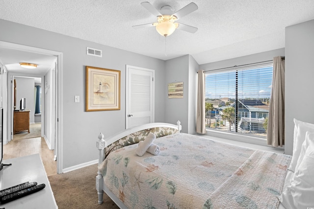 bedroom featuring ceiling fan, a closet, carpet, and a textured ceiling