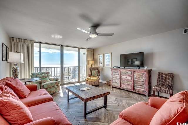 living room featuring light parquet flooring, ceiling fan, and a healthy amount of sunlight