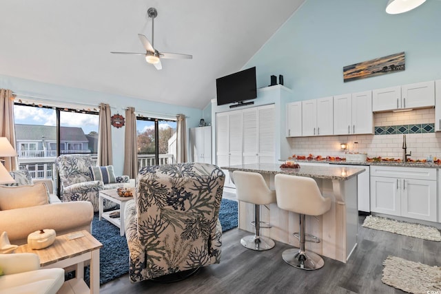 living room featuring dark hardwood / wood-style flooring, ceiling fan, sink, and high vaulted ceiling