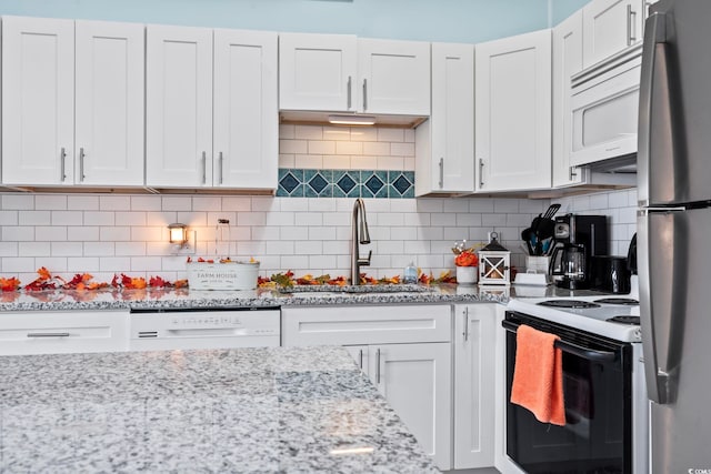 kitchen with white appliances, sink, tasteful backsplash, light stone counters, and white cabinetry