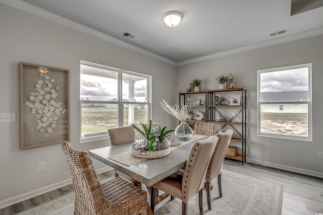 dining area with light hardwood / wood-style floors and ornamental molding