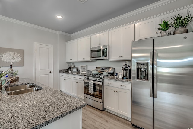 kitchen featuring stainless steel appliances, crown molding, sink, dark stone countertops, and white cabinets