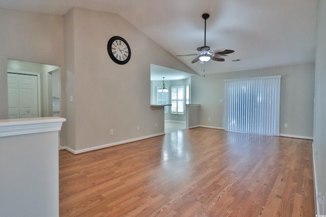 unfurnished living room with high vaulted ceiling, ceiling fan with notable chandelier, and light wood-type flooring