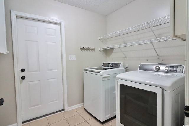 clothes washing area featuring light tile patterned flooring, washer and dryer, and a textured ceiling