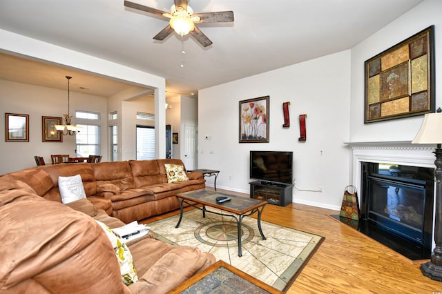 living room with wood-type flooring and ceiling fan with notable chandelier