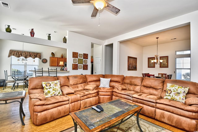 living room with light wood-type flooring and ceiling fan with notable chandelier