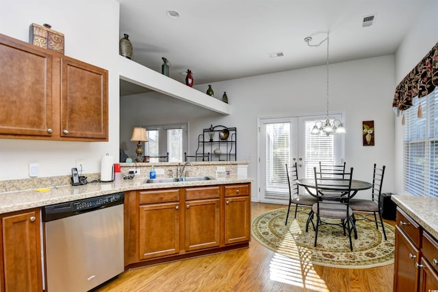 kitchen with a chandelier, sink, stainless steel dishwasher, light wood-type flooring, and decorative light fixtures