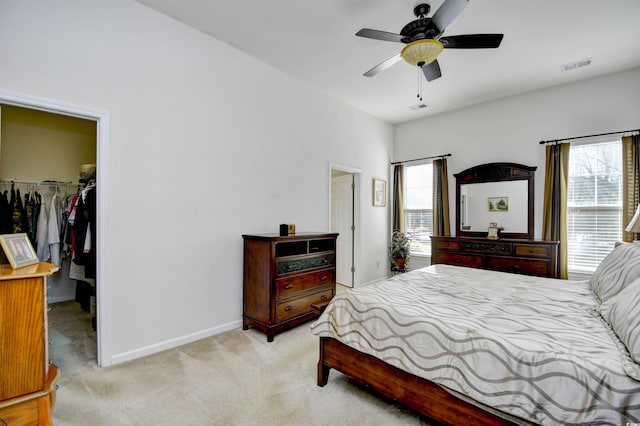 bedroom with ceiling fan, a closet, a spacious closet, and light colored carpet