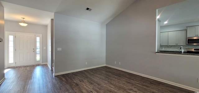 foyer featuring dark wood-type flooring, sink, and lofted ceiling