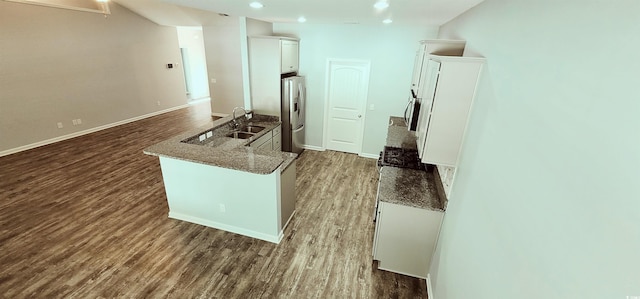 kitchen featuring stainless steel fridge, sink, white cabinets, dark wood-type flooring, and dark stone countertops