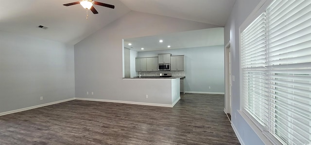 unfurnished living room featuring dark hardwood / wood-style flooring, lofted ceiling, ceiling fan, and plenty of natural light