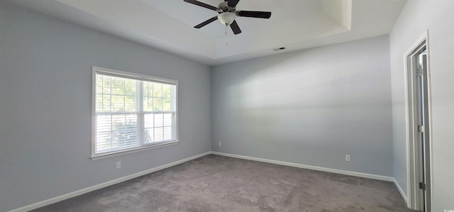 spare room featuring ceiling fan, light colored carpet, and a raised ceiling