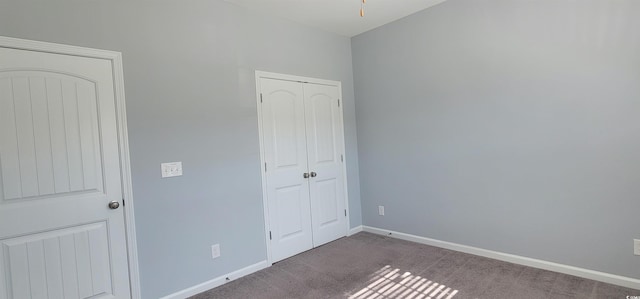 unfurnished bedroom featuring a closet and dark colored carpet