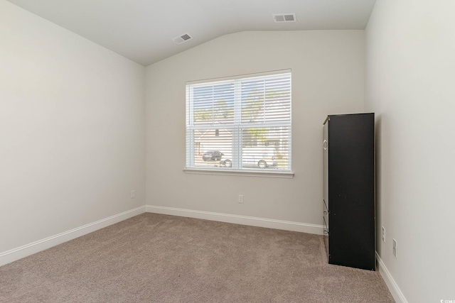 carpeted empty room featuring vaulted ceiling