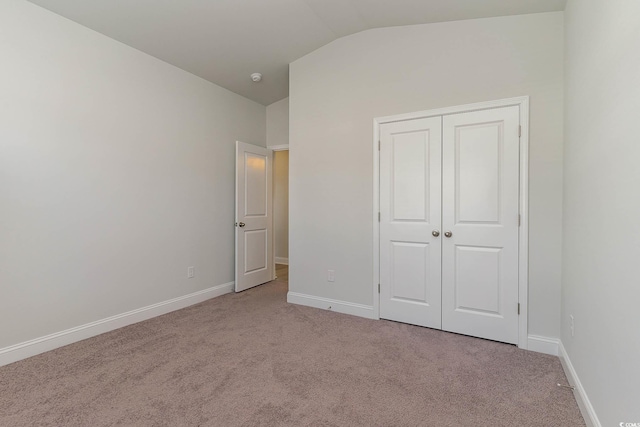 unfurnished bedroom with a closet, vaulted ceiling, and light carpet