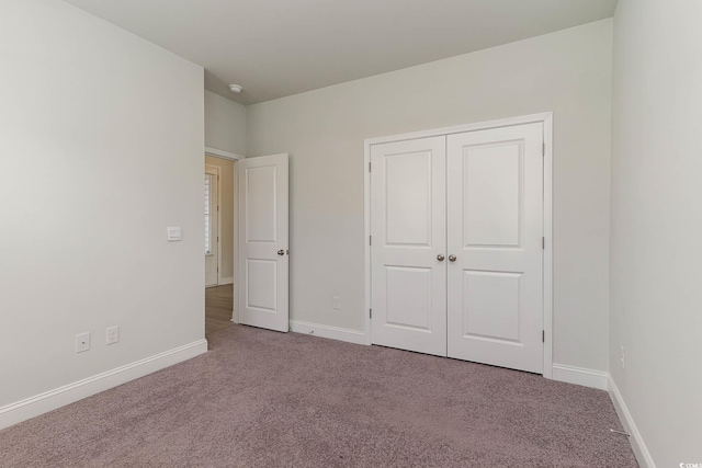 unfurnished bedroom featuring light carpet and a closet