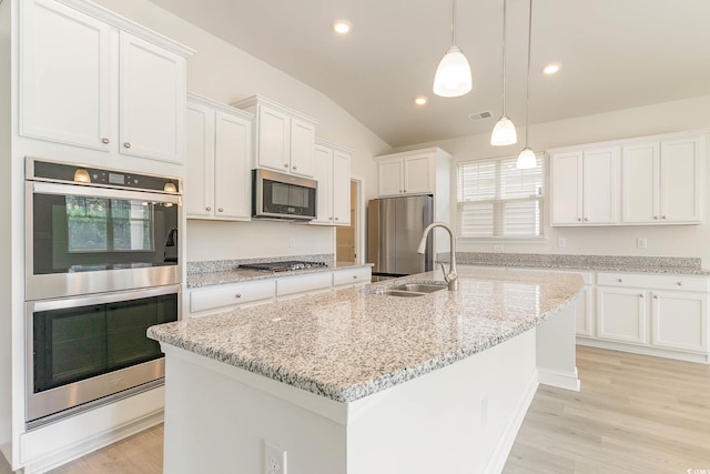 kitchen featuring a kitchen island with sink, hanging light fixtures, stainless steel appliances, and white cabinets