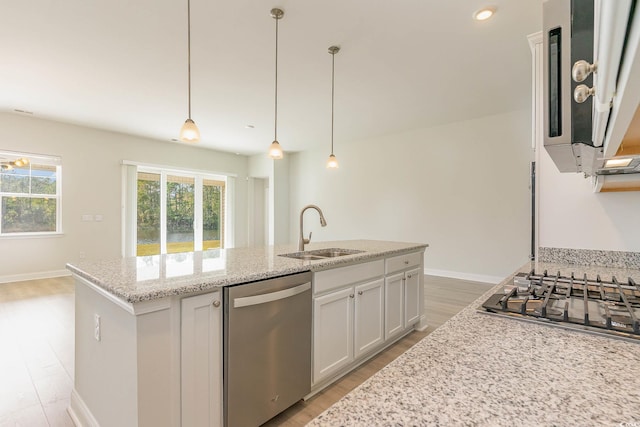 kitchen with stainless steel appliances, an island with sink, sink, and pendant lighting