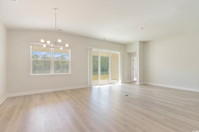 empty room featuring an inviting chandelier and light hardwood / wood-style floors