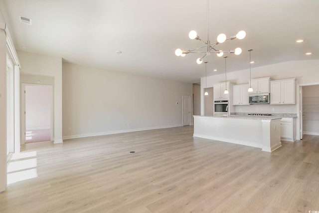 kitchen with an island with sink, oven, white cabinets, hanging light fixtures, and light hardwood / wood-style floors