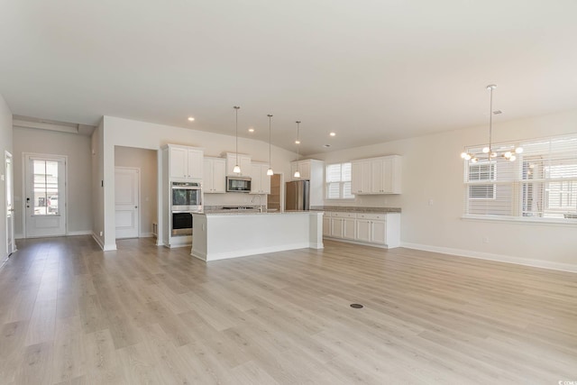 unfurnished living room featuring a chandelier and light hardwood / wood-style flooring