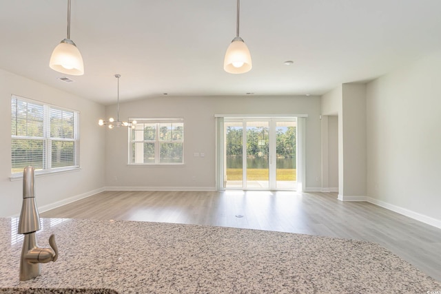 unfurnished room with plenty of natural light, a notable chandelier, and light wood-type flooring