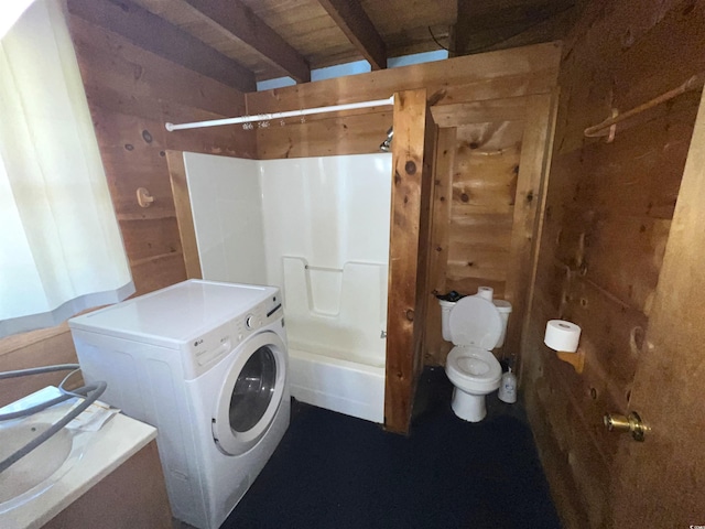 bathroom featuring toilet, washer / clothes dryer, beamed ceiling, and wooden walls