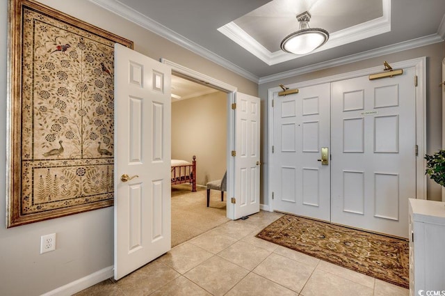 tiled entrance foyer featuring a tray ceiling and ornamental molding