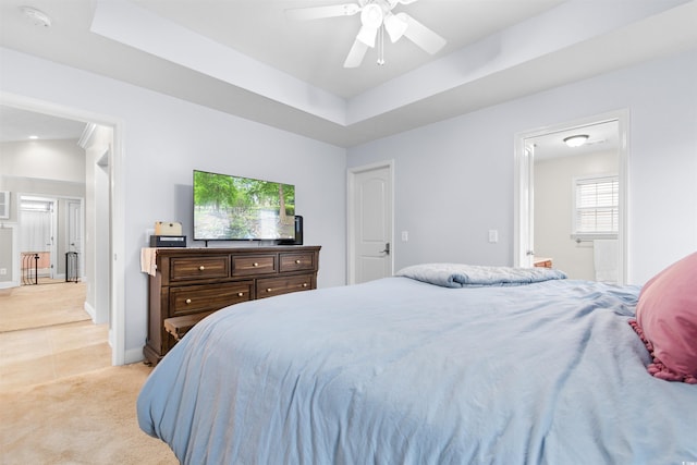 bedroom featuring connected bathroom, ceiling fan, light colored carpet, lofted ceiling, and a tray ceiling