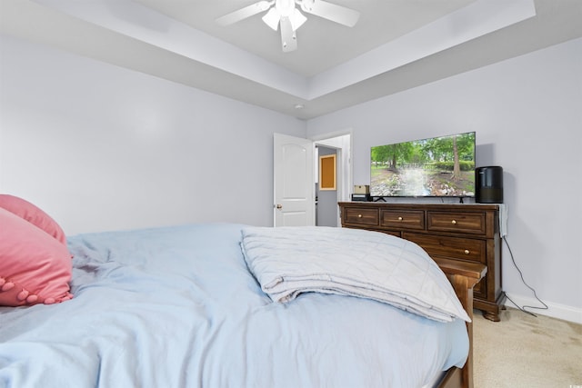 carpeted bedroom with ceiling fan and a raised ceiling