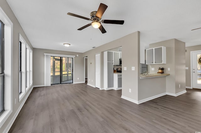 unfurnished living room featuring wood-type flooring, ceiling fan, and sink